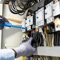 Dłonie w rękawicach izolacyjnych montujące złącza elektryczne w rozdzielni