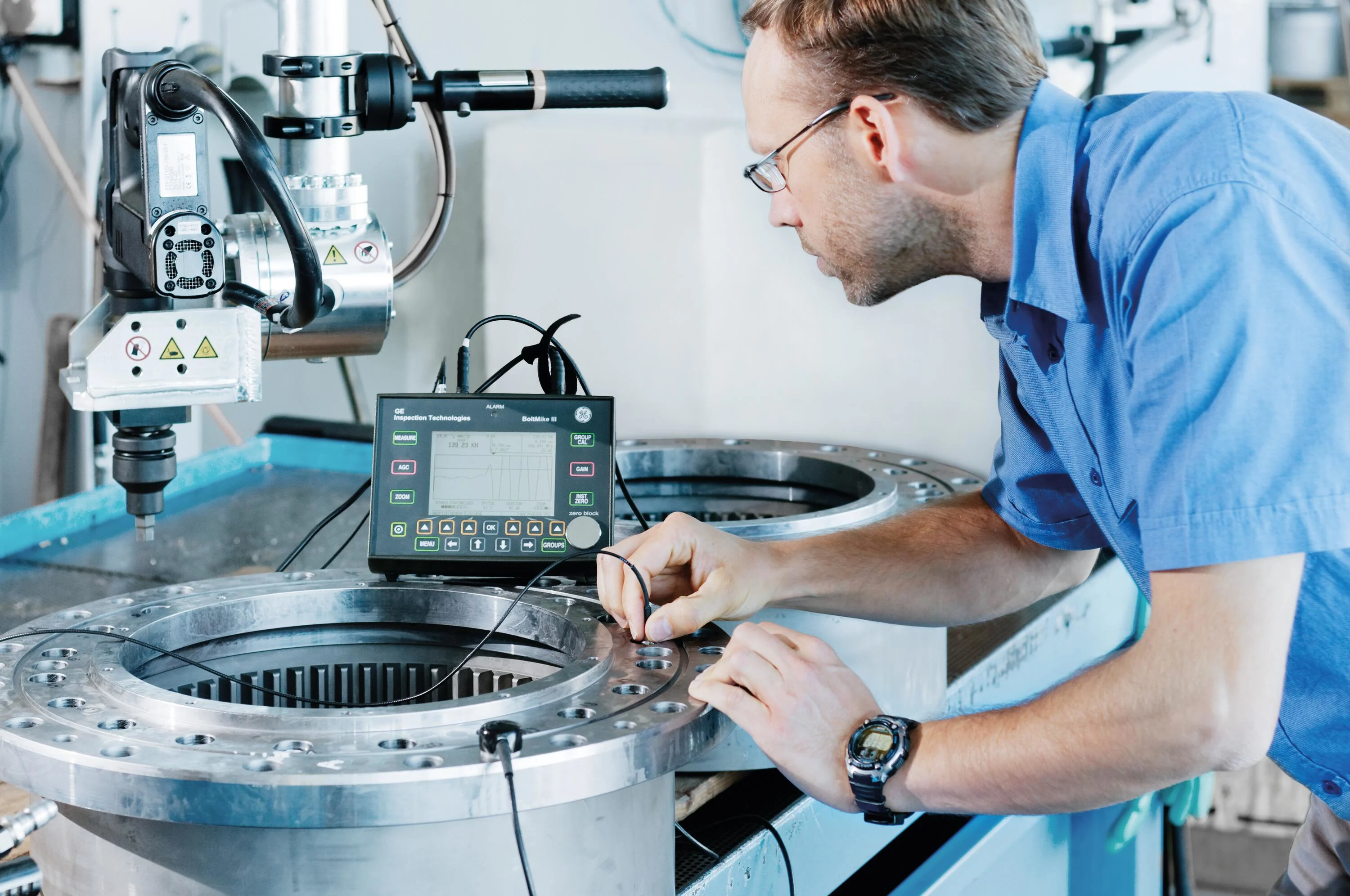 A male engineer uses a probe for ultrasonic preload measurement in an industrial application.