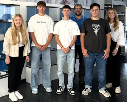 Gruppe von Auszubildenden und einem Betreuer bei Bossard Deutschland, posierend in einem modernen Ausstellungsraum.