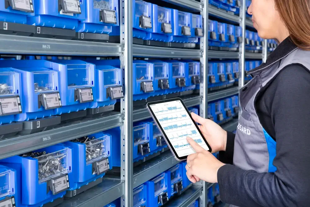 Person is checking stock information on a tablet in front of C-part bins