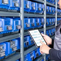 Person is checking stock information on a tablet in front of C-part bins
