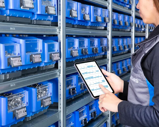 Person is checking stock information on a tablet in front of C-part bins