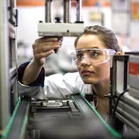 Eine Frau im Laborkittel arbeitet konzentriert an einer Maschine in einem modernen Labor.
