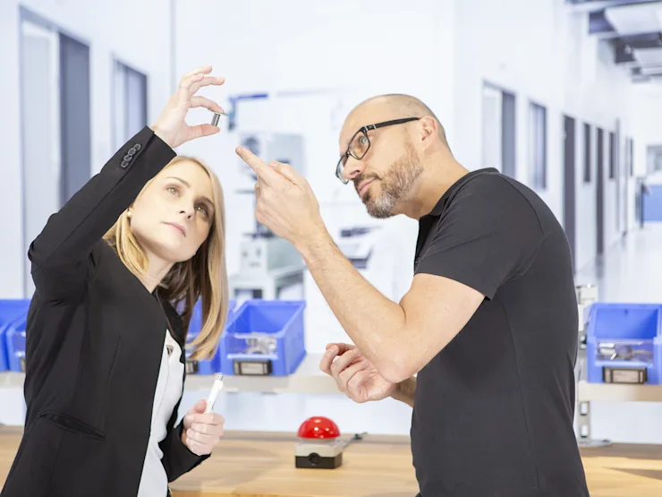A man and a woman holding a bighead fastener, looking at it and discussing