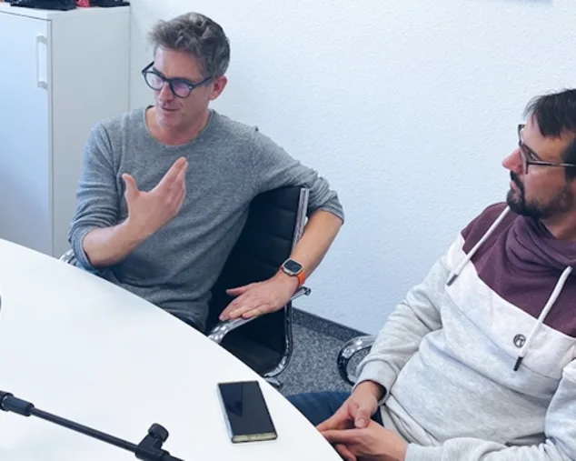Jürgen Steiner und Jan Wilhelm sitzen zusammen im Podcast Raum und unterhalten sich