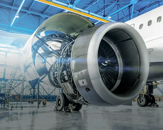Eine Nahaufnahme eines Flugzeugmotors in einem Hangar mit blauen Wänden, die seine mechanischen Merkmale hervorhebt.