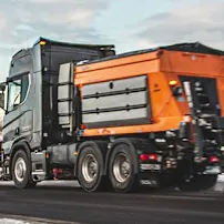 Epoke Winterdienstgeräte sind auf der Straße neben den schneebedeckten Bergen unterwegs.