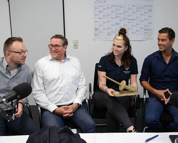 Gruppe von Fachleuten bei einer Podcast-Aufnahme, eine Person hält ein Holzmodell