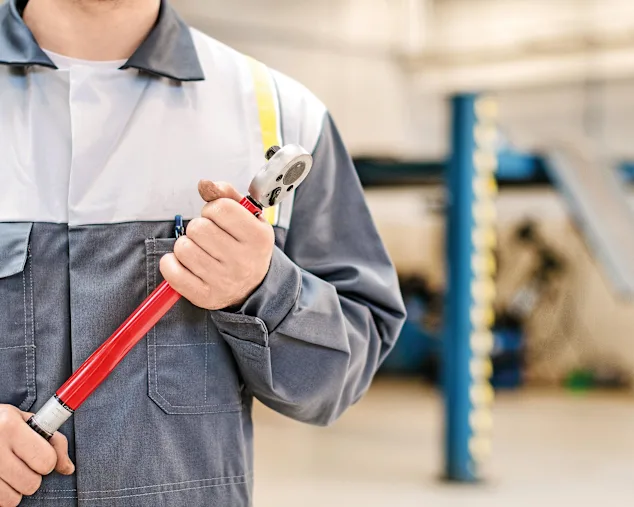 Mécanicien avec clé dynamométrique dans un atelier de réparation automobile.