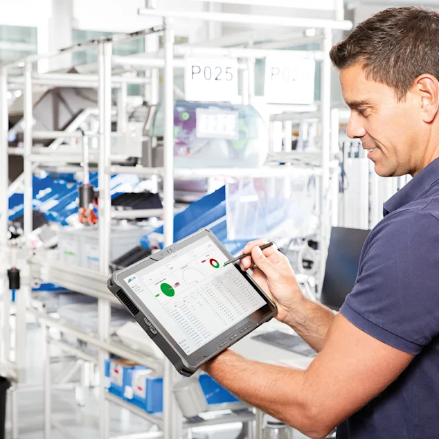 Smart Factory Assembly Guy med tablet i hænderne kigger på dashboardet med realtidsdata