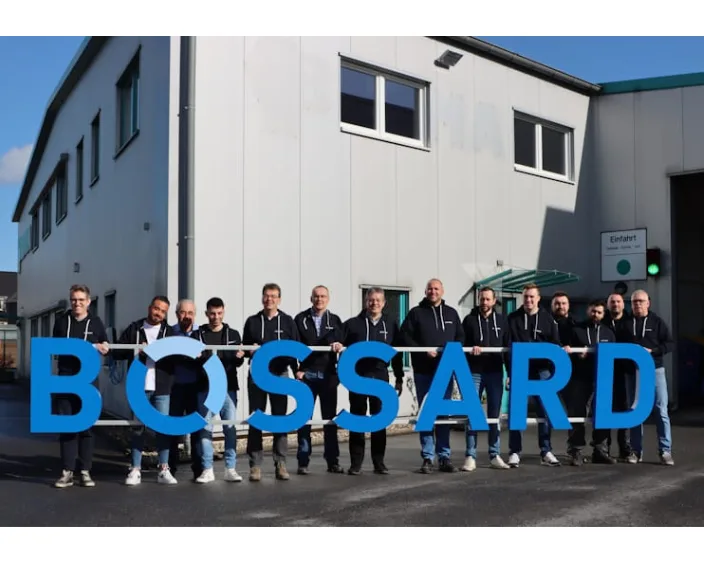 Gruppe von Menschen mit BOSSAARD-Logo vor einem Firmengebäude.