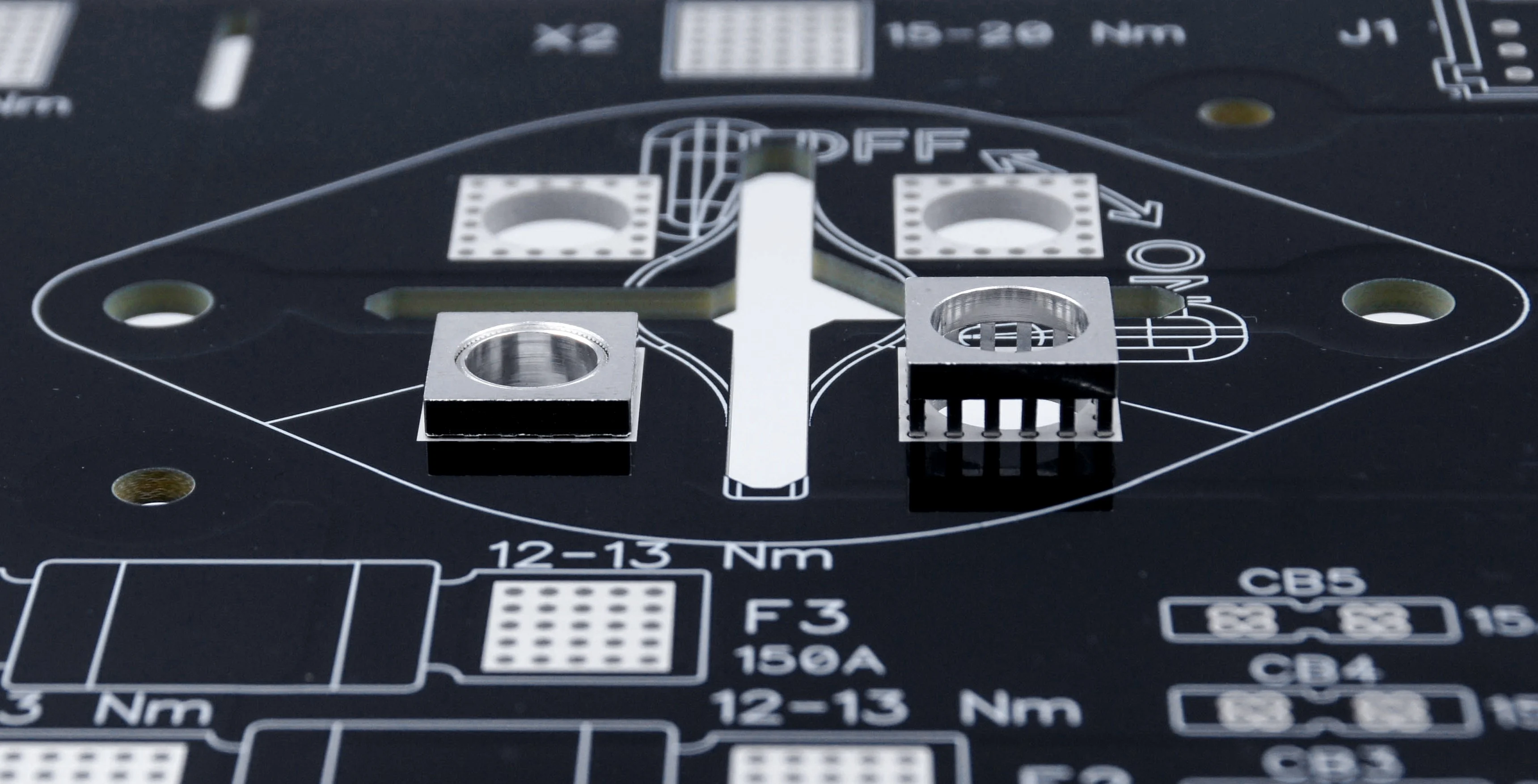Close-up of a black PCB with MTCON power elements, three already pressed in, one still to be assembled