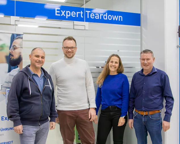 Marcus Ritter, Tobias Engelberg, Maja Matzke und Horst Sälzle stehen nebeneinander vor einer matt folierten Sichtschutzscheibe mit der Aufschrift "Expert Teardown"