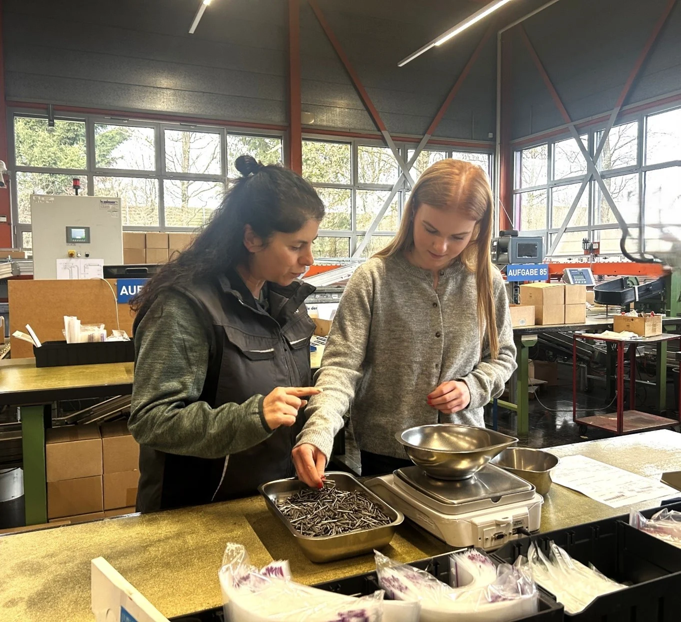 Zwei Mädchen die während ihrem Ferienjobs Schrauben abwägen und vorbereiten für die Verpackung