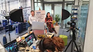 Egy csoport laptopokon dolgozó egyén a Bossard videófelvételi stúdiójában egy aktív felvételi munkamenet során.