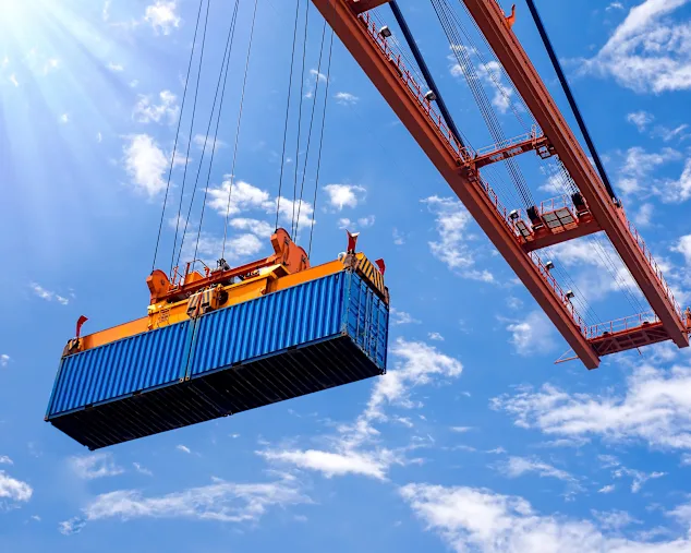 Low angle view of a container on a crane against blue sky.