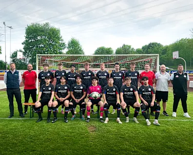 Mannschaftsfoto des SC Vöhringen auf dem Fußballplatz vor einem Tor, mit Spielern und Betreuern in Bossard-Trikots.