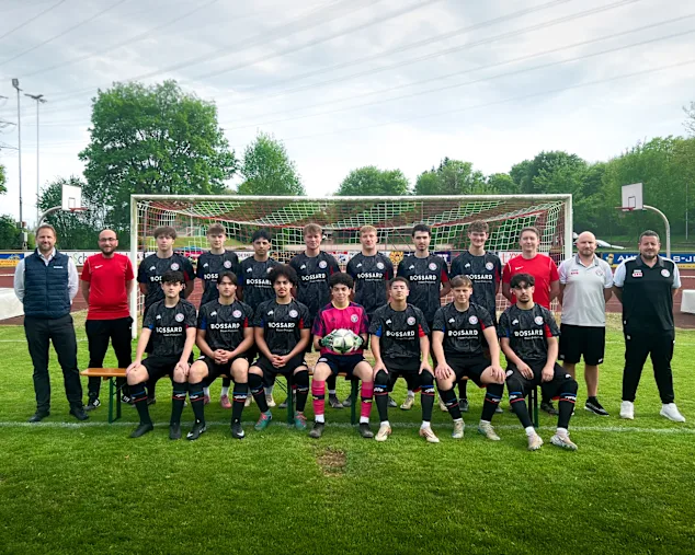 Mannschaftsfoto des SC Vöhringen auf dem Fußballplatz vor einem Tor, mit Spielern und Betreuern in Bossard-Trikots.