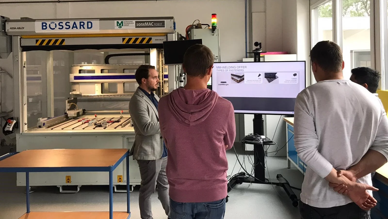 Vier Personen stehen vor einer Ultraschallschweißmaschine zur Befestigung von Verbundwerkstoffen und Leichtbau.