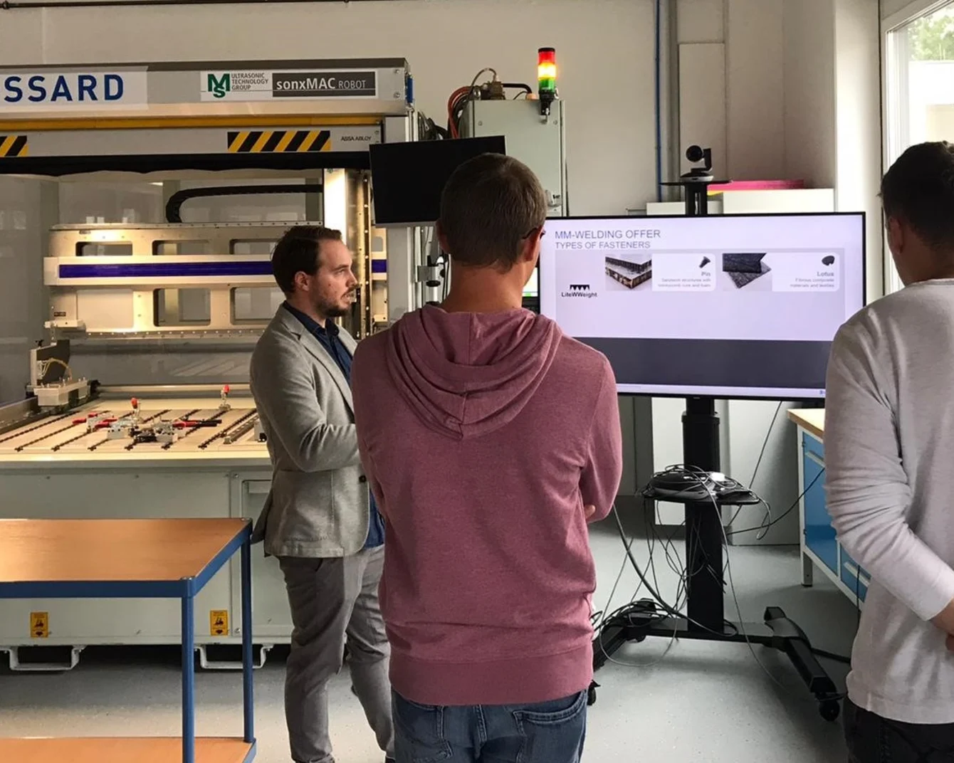 Vier Personen stehen vor einer Ultraschallschweißmaschine zur Befestigung von Verbundwerkstoffen und Leichtbau.