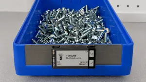 Bac de rangement en plastique bleu rempli de vis à tête hexagonale en métal, avec une étiquette intelligente indiquant le numéro de produit et la taille.