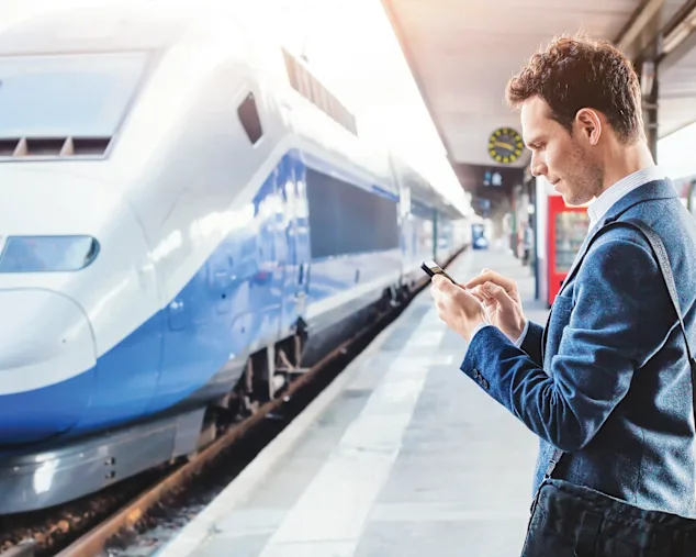 A man on a railway station using an electronic device