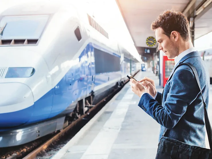 A man on a railway station using an electronic device