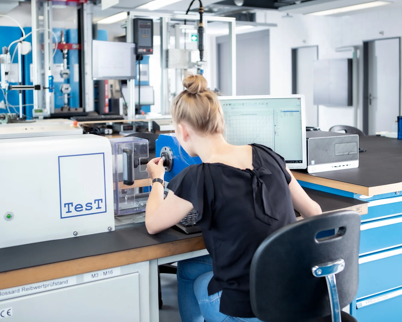 Person prepares a friction coefficient test at the desk in a technical testing laboratory.