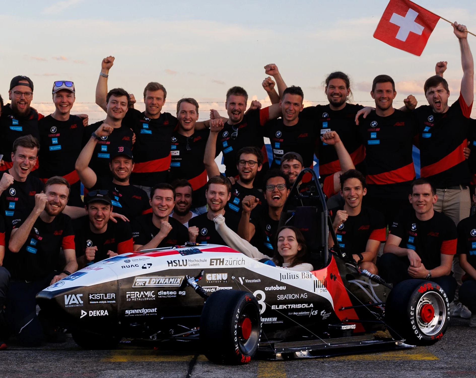 Das AMZ Team steht zusammen mit ihrem Auto für ein Gruppenfoto, voller Energie und Begeisterung.