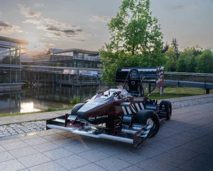 Rennwagen des Formula Student Teams vor moderner Architektur.