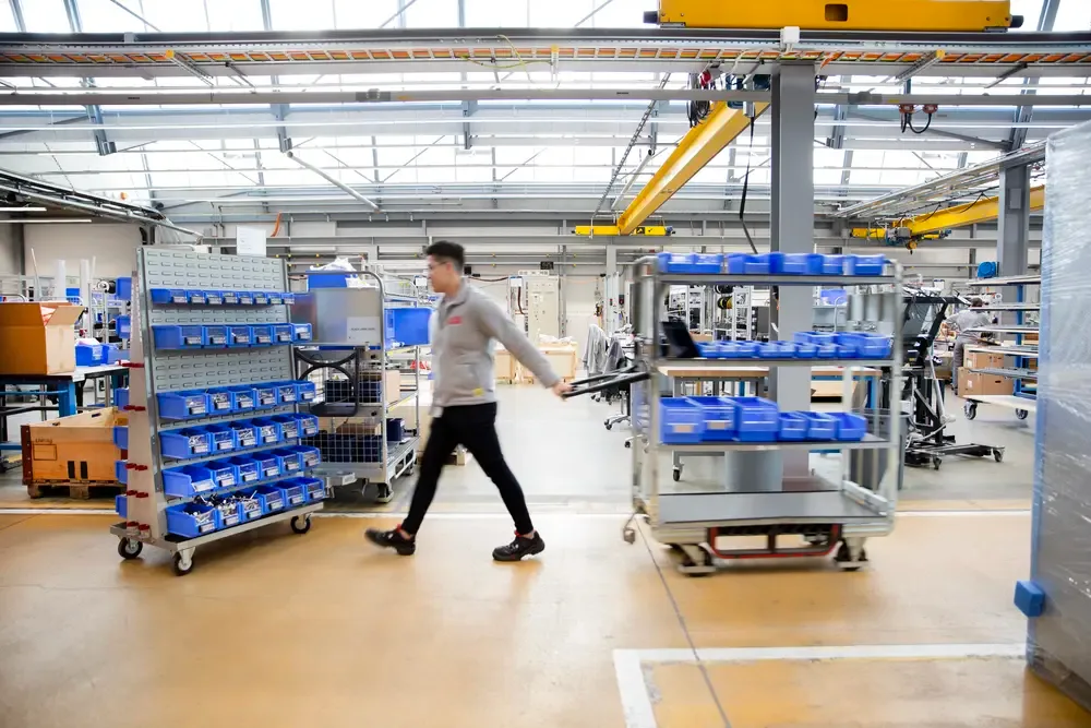 Opérateur logistique traversant un entrepôt moderne pour réapprovisionner les bacs dans l'atelier de production