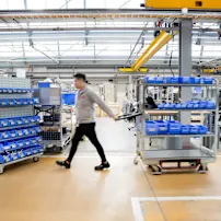 Milk runner walking through modern warehouse facility to refill bins on the shop floor