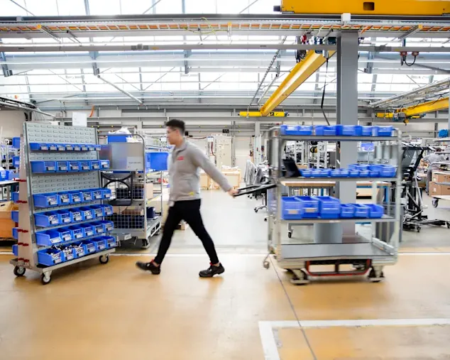 Milk runner walking through modern warehouse facility to refill bins on the shop floor
