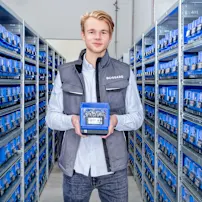 Man standing in supermarket area holding a SmartBin Cloud in its hands.