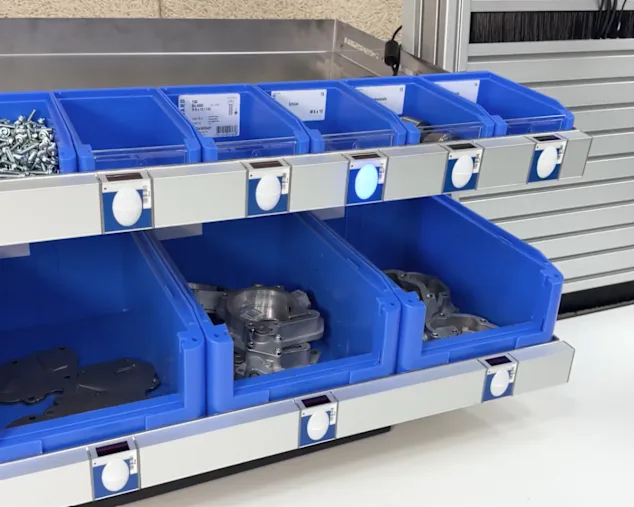 Systém Bossard Pick-to-Light s modrými zásobníky na pracovišti v montážní oblasti