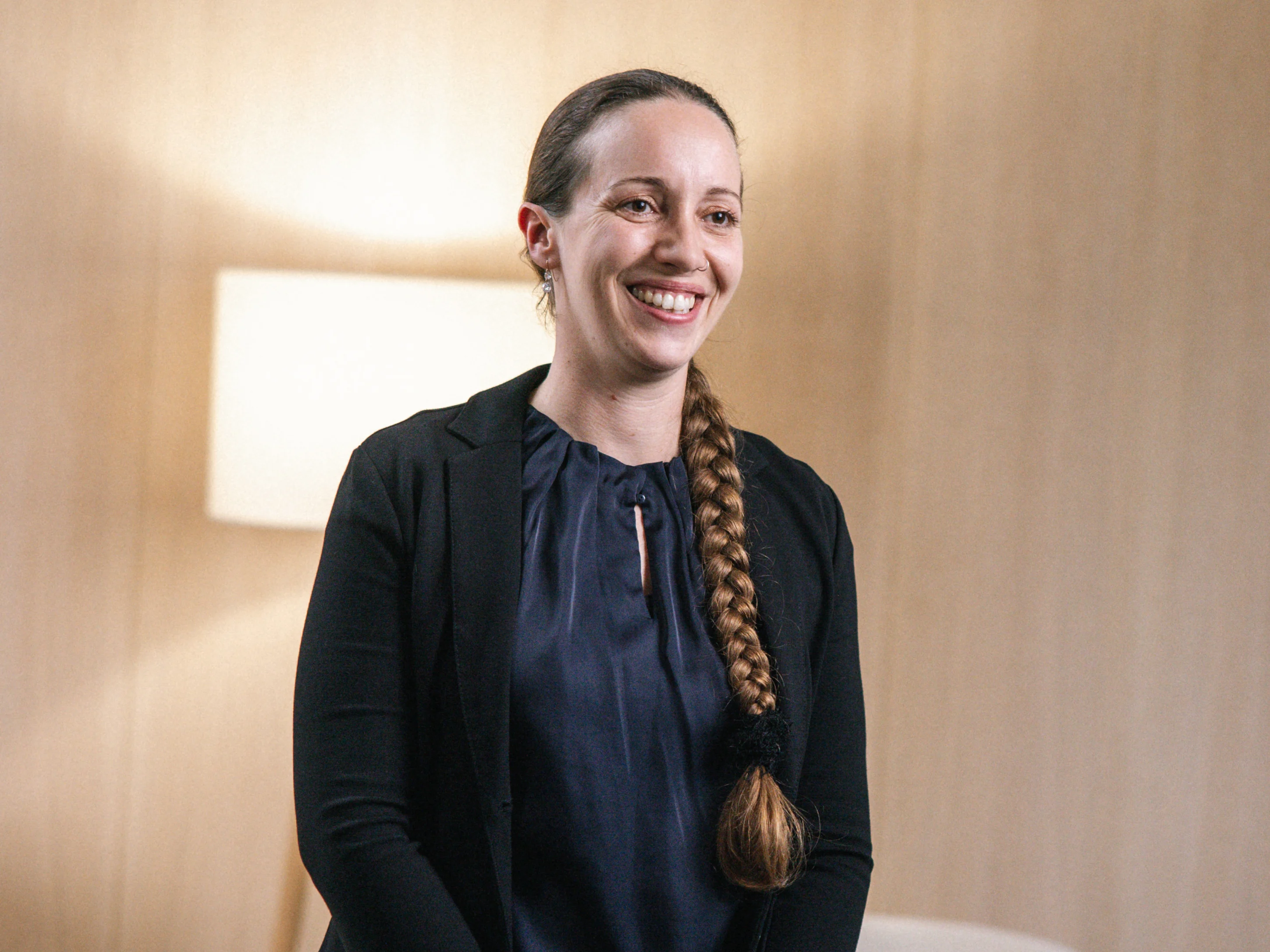 Eine Frau mit einem Zopf steht vor einer Lampe und strahlt eine ruhige Atmosphäre aus.