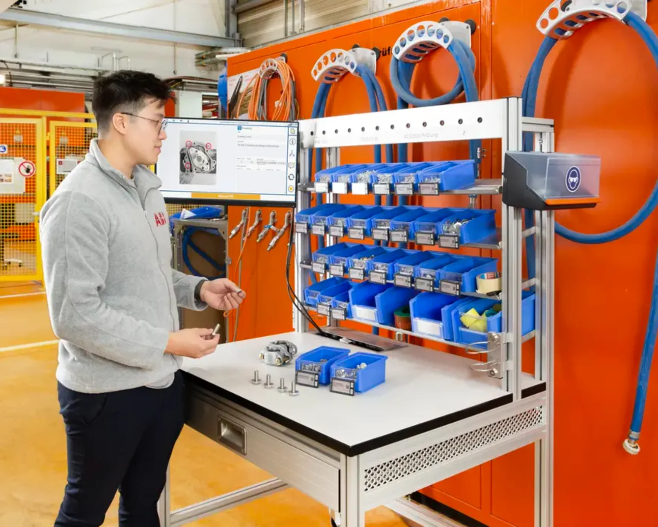 Assembly worker at workstation with SmartLabel Cloud bins and work instruction displayed on screen.