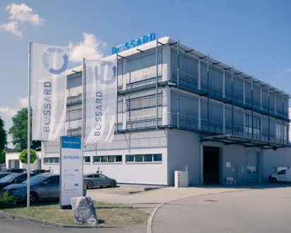 Außenansicht eines modernen Firmengebäudes mit Bossard Fahnen und Beschilderung.