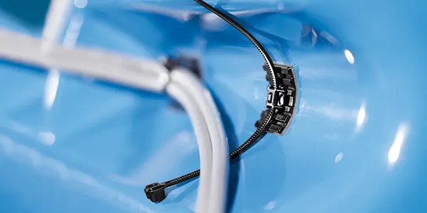 Close-up of the HellermannTyton cable tie mount FlexTack on blue background, showcasing the reliable fixing of cable ties in place