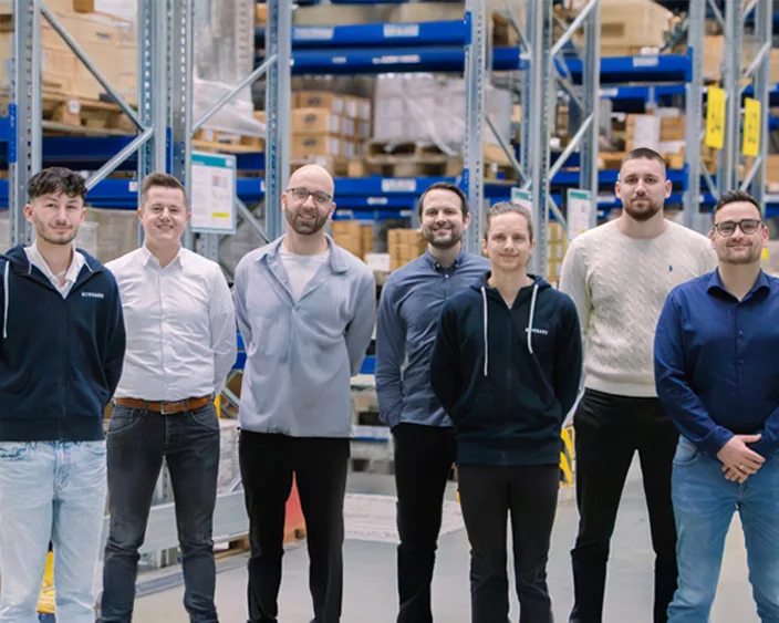 Kunststoff-Segment Team von steht in einem Lagergang vor vollen Regalen