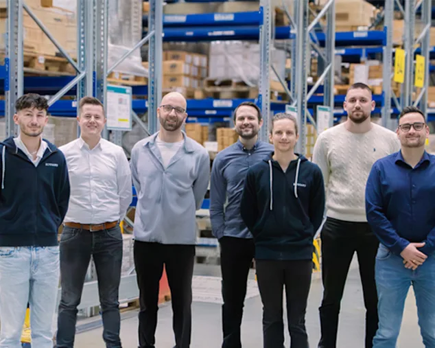 Kunststoff-Segment Team von steht in einem Lagergang vor vollen Regalen