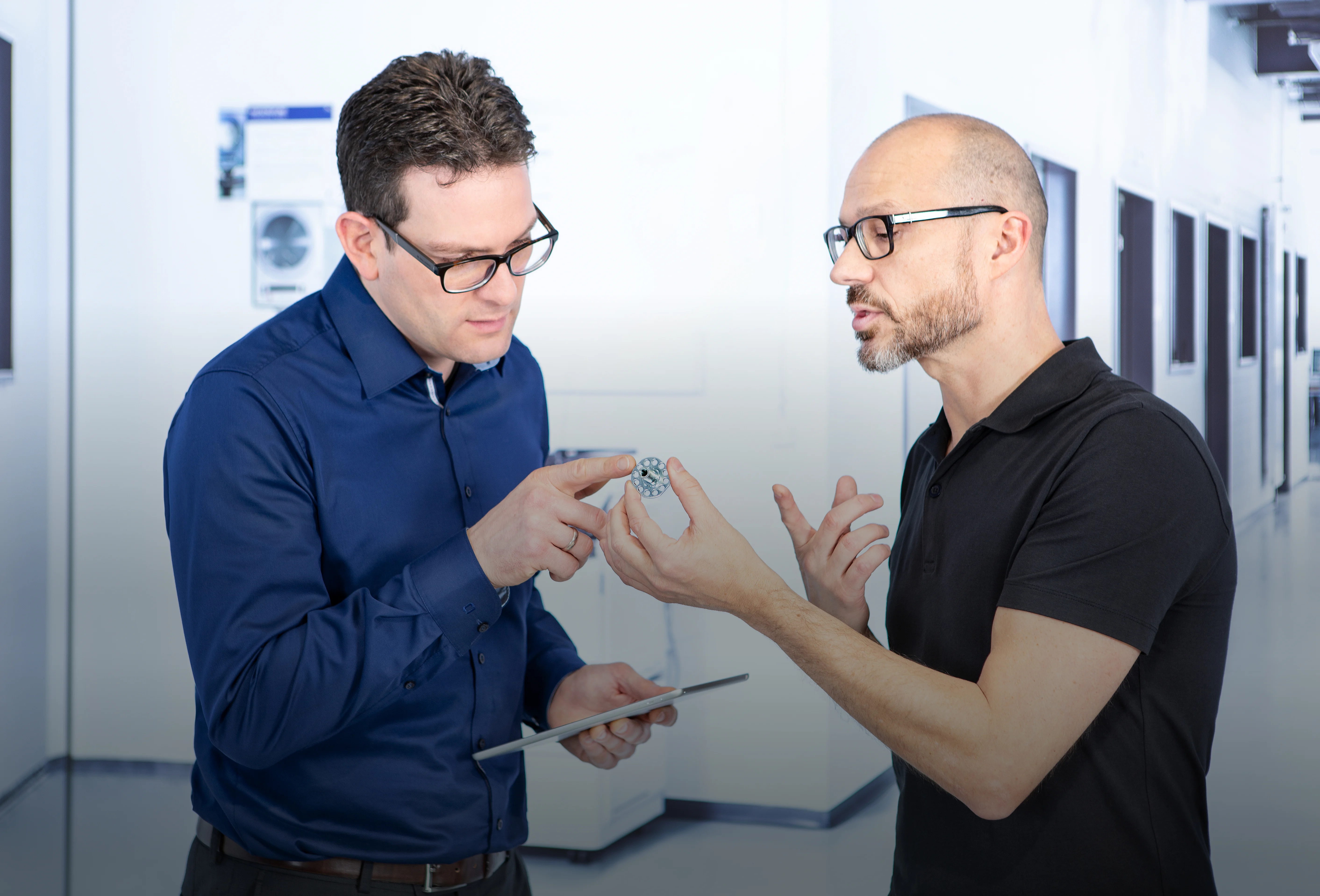 Två personer diskuterar designen av en fästanordning.