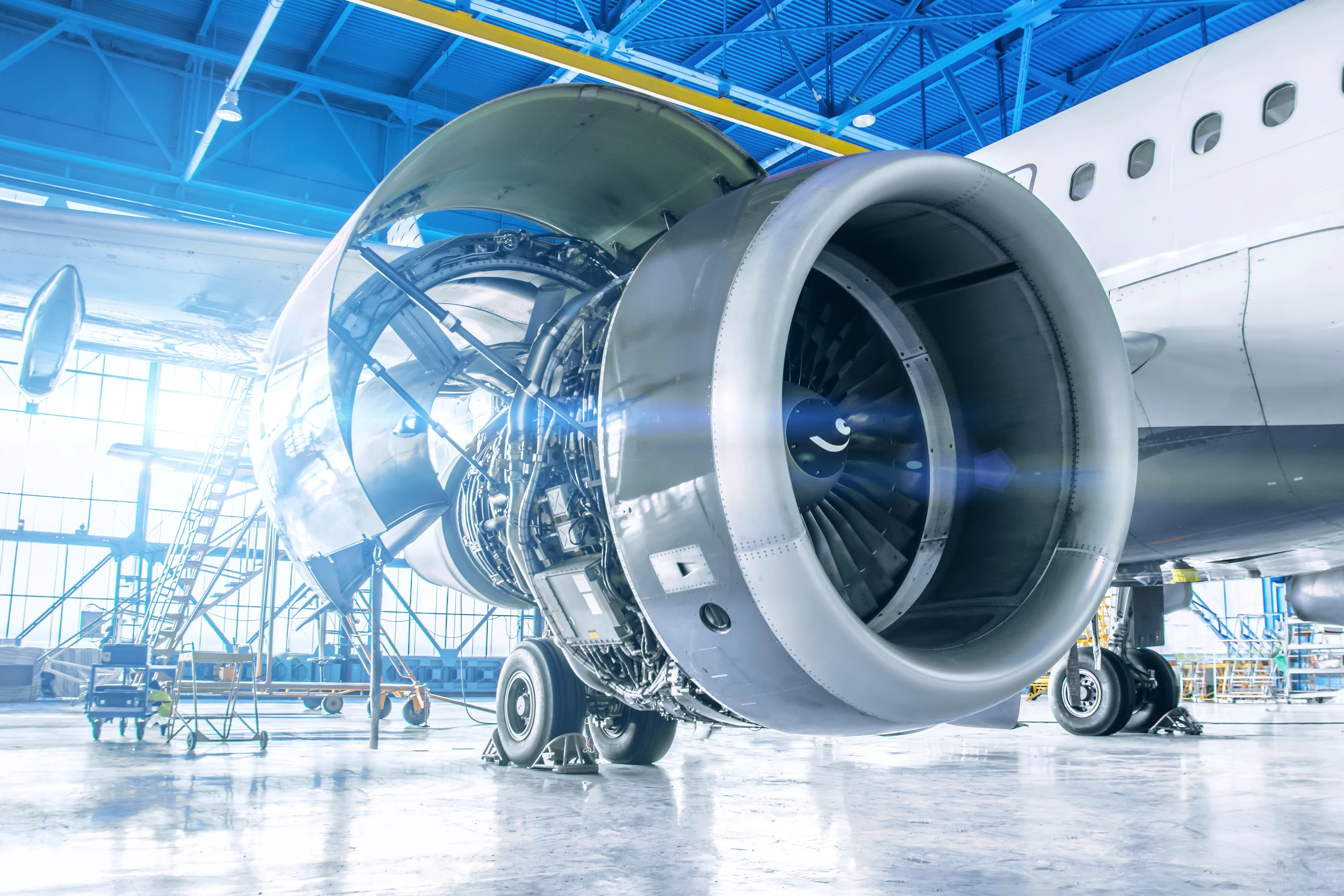 A close-up of an airplane engine situated in a hangar with blue walls, highlighting its mechanical features.