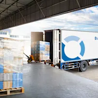 White Bossard delivery truck being loaded with wrapped pallets in warehouse loading bay.