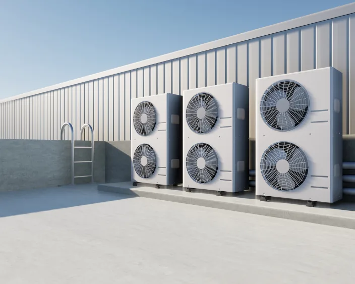 Drei große Klimageräte auf einem Gebäudedach.