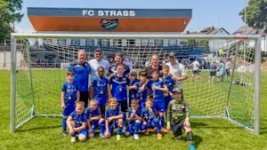 Jugendmannschaft des FC Strass mit Trainern vor einem Fußballtor nach einem Turnier, mehrere Spieler tragen Medaillen.