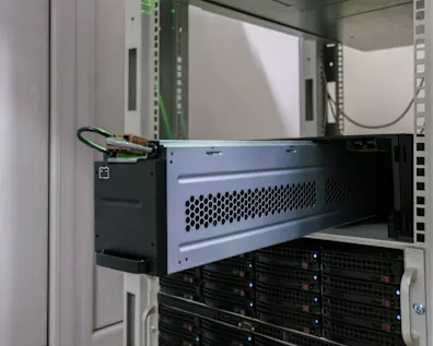 Equipos de servidor con hardware montado en rack negro y gris, rejillas de ventilación y luces LED azules en un armario de servidor blanco