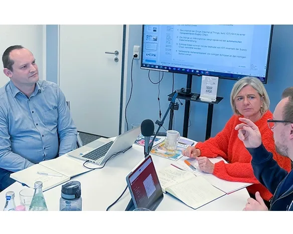 Eine Gruppe von drei Personen diskutiert vor einem Mikrofon