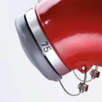 Zwei Reihen roter Hydranten mit silbernen Kappen und Nummern, seitlich betrachtet, die ein symmetrisches Muster bilden.