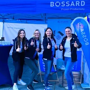 Vier lächelnde Frauen vor einem blauen Bossard-Zelt bei einer Veranstaltung